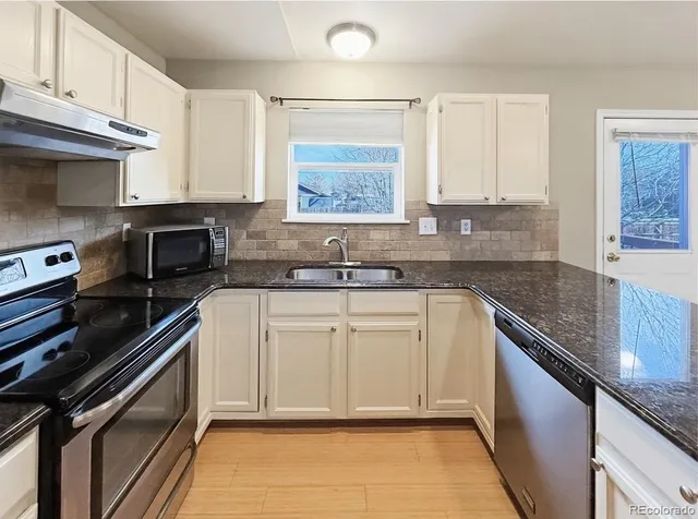 a kitchen with granite countertop a sink stove and cabinets