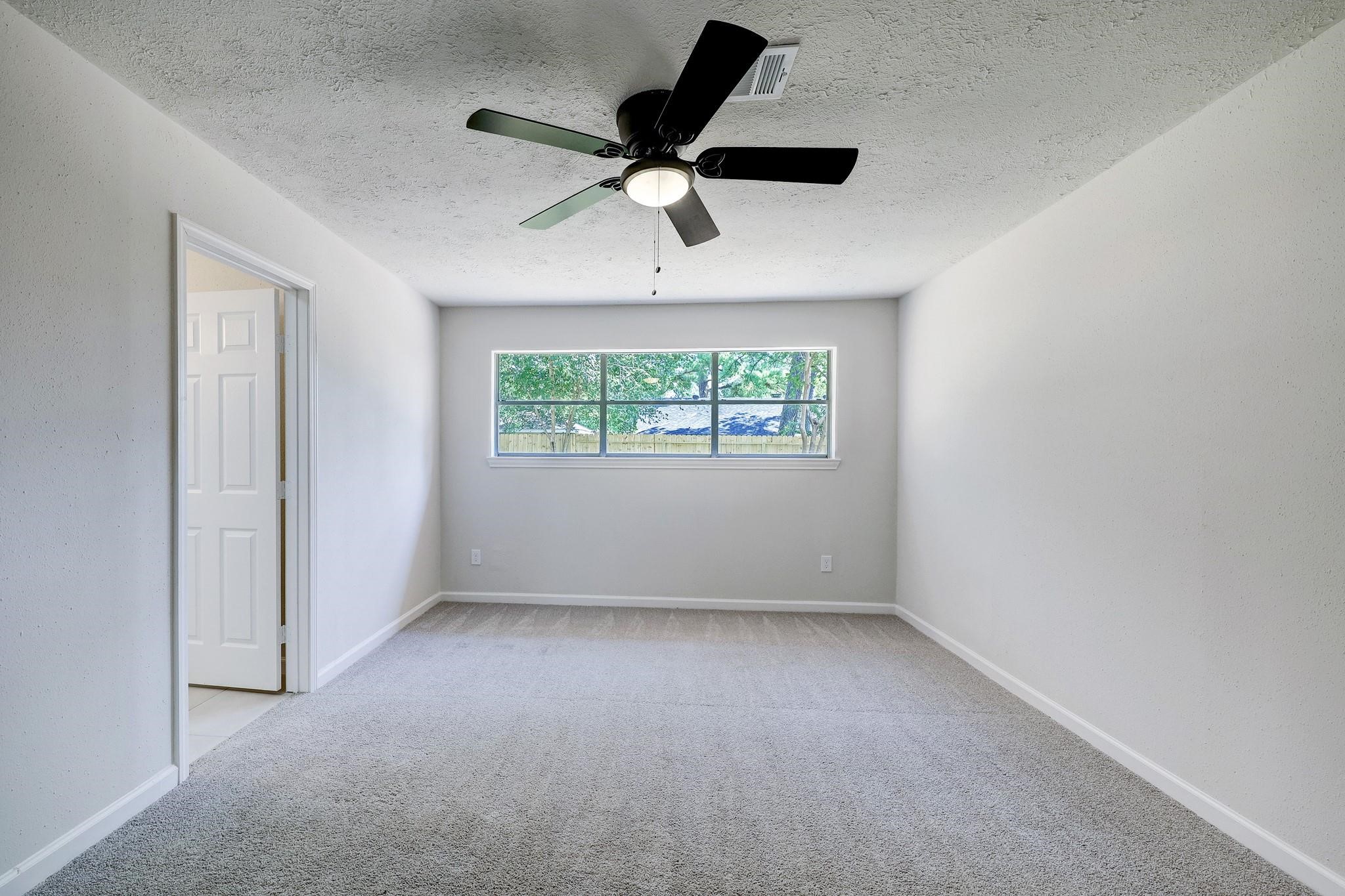 9723 Galston Lane Spring, TX 77379 - Photo 20 of 24 The primary bedroom features a broad window that frames views of the backyard and a modern ceiling fan. The room's proportions offer flexibility for various furniture arrangements.