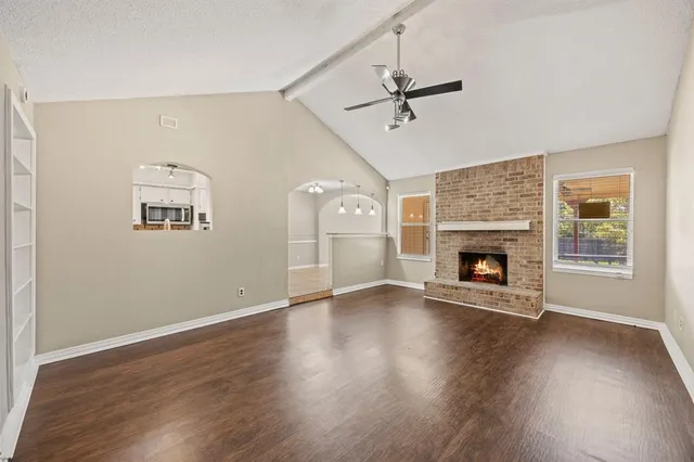 an empty room with wooden floor cabinet and windows