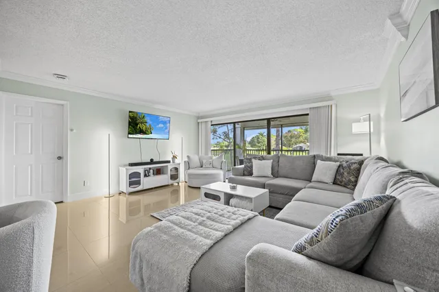 a living room with furniture a flat screen tv and a floor to ceiling window