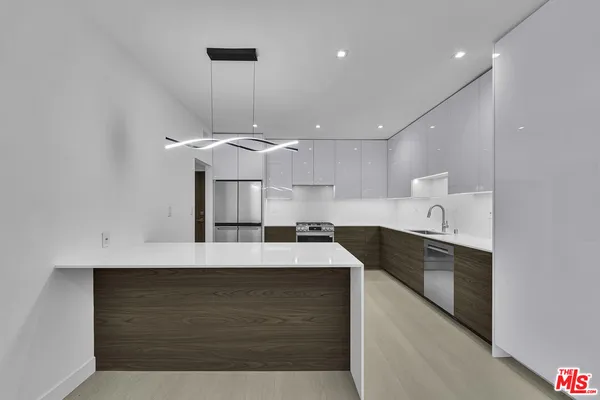 a large kitchen with kitchen island a sink stainless steel appliances and a chandelier