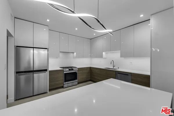 a kitchen with granite countertop a refrigerator stove top oven and sink