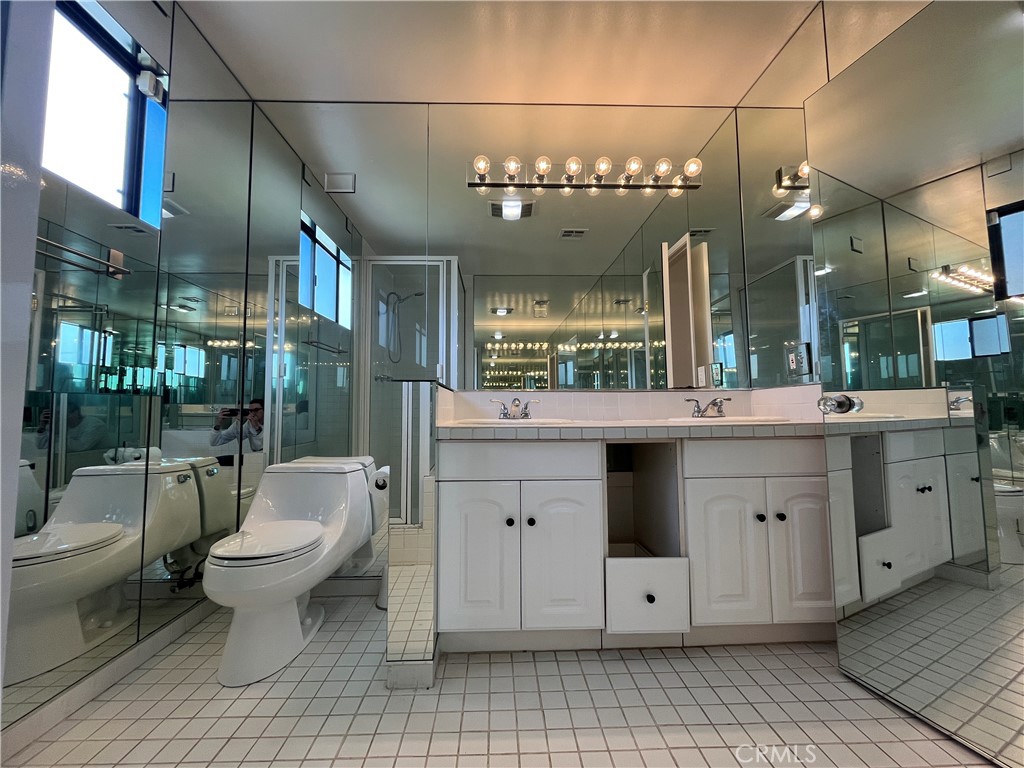 18029 Santa Rita Street Encino, CA 91316 - Photo 16 of 20 a bathroom with a double vanity sink a toilet a mirror and shower