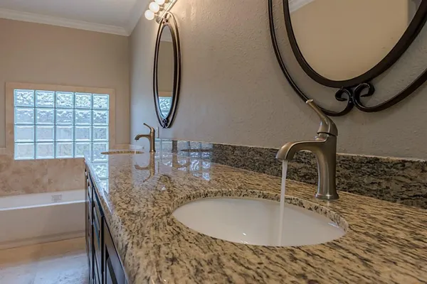 a bathroom with a granite countertop sink and mirror