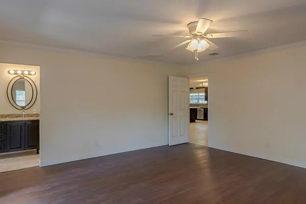 an empty room with wooden floor fan and windows