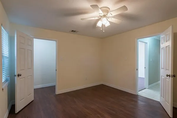 an empty room with wooden floor and a ceiling fan