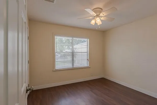 a view of an empty room with window and wooden floor