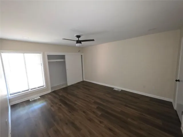 a view of empty room with wooden floor and fan