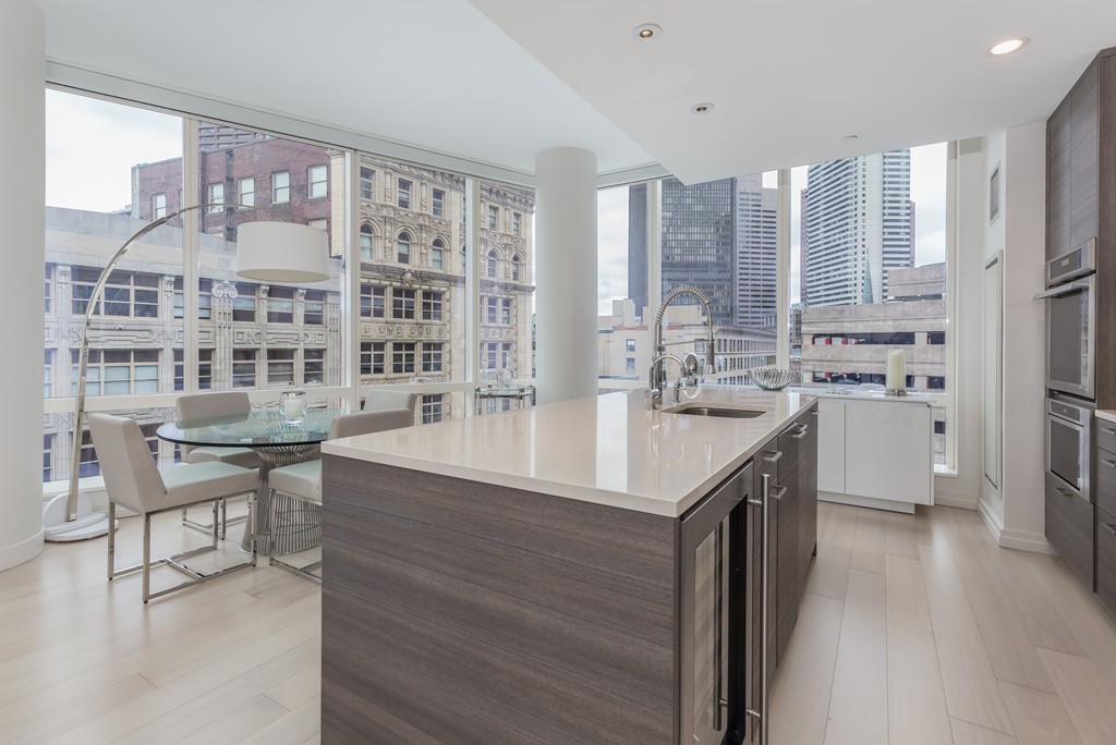 1 Franklin Street, Unit 1004 Boston, MA 02110 - Photo 7 of 24 a kitchen with kitchen island granite countertop a sink and a stove top oven