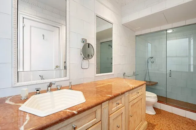 a bathroom with a granite countertop sink mirror vanity and toilet