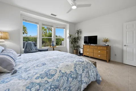 a bedroom with a bed flat screen tv and a large window