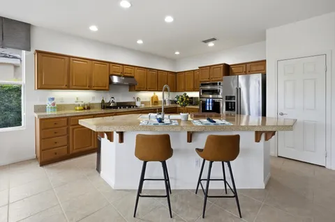 a kitchen with stainless steel appliances kitchen island granite countertop a stove a sink a refrigerator and a refrigerator