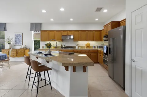 a kitchen with stainless steel appliances granite countertop a stove a sink a refrigerator and a refrigerator
