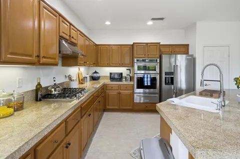a kitchen with stainless steel appliances granite countertop a sink refrigerator and cabinets