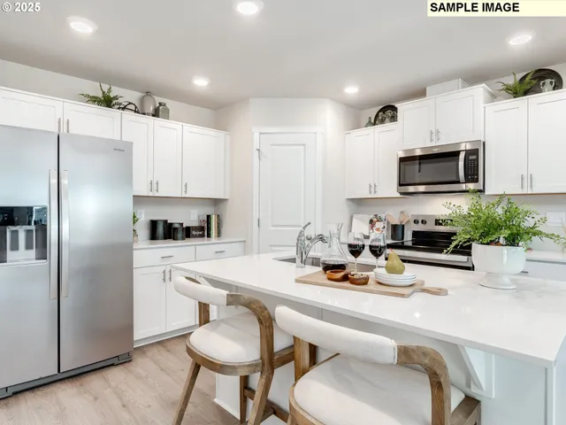 a kitchen with a refrigerator a stove a sink and chairs