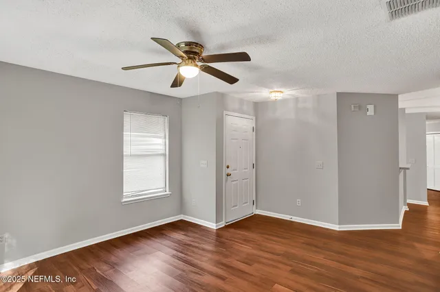 a view of an empty room with wooden floor and a window