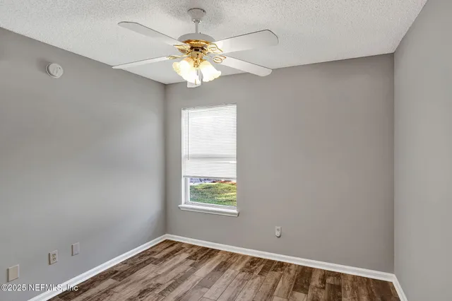 an empty room with a window and wooden floor