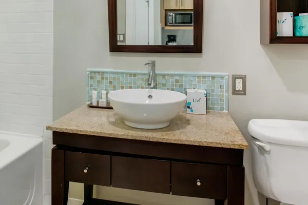 a bathroom with a granite countertop sink a toilet and mirror