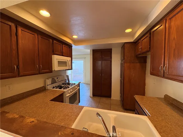 a kitchen with stainless steel appliances granite countertop a refrigerator a stove and a sink with wooden cabinets