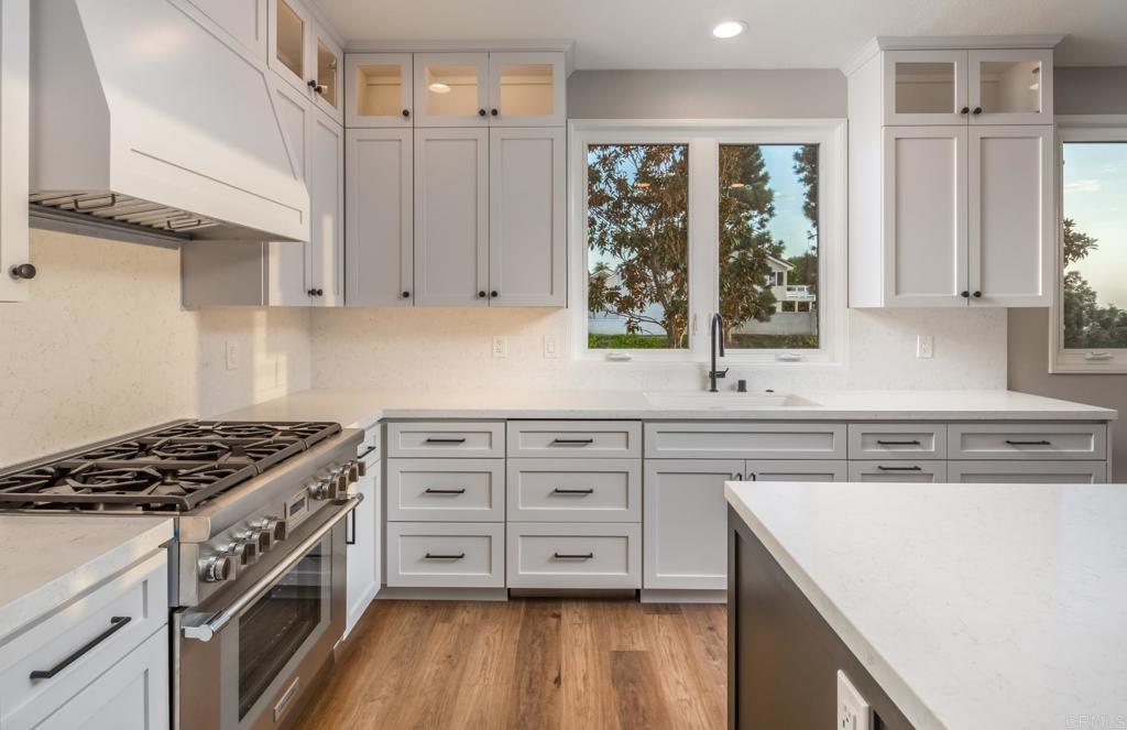1808 Amalfi Drive Encinitas, CA 92024 - Photo 5 of 33 a kitchen with granite countertop a stove a sink and white cabinets with wooden floor