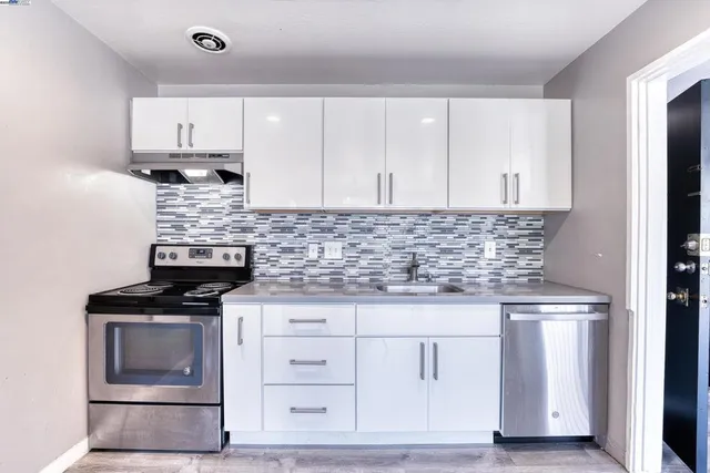 a kitchen with granite countertop white cabinets and stainless steel appliances