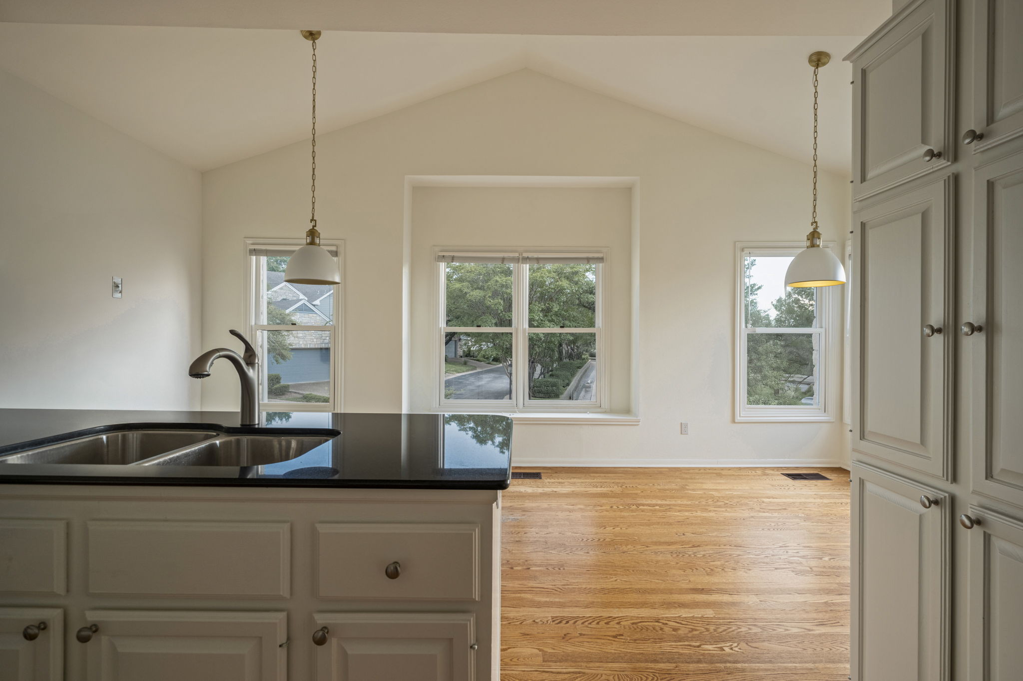 6010 Long Champ Court, Unit 113 Austin, TX 78746 - Photo 14 of 25 Kitchen featuring plenty of natural light, light wood-style flooring, hanging light fixtures, vaulted ceiling, and dark stone countertops