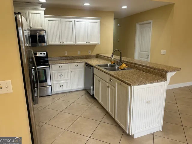 a kitchen with granite countertop a sink cabinets and stainless steel appliances