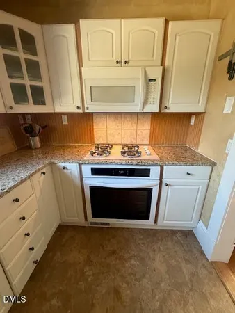 a kitchen with stainless steel appliances a stove and white cabinets