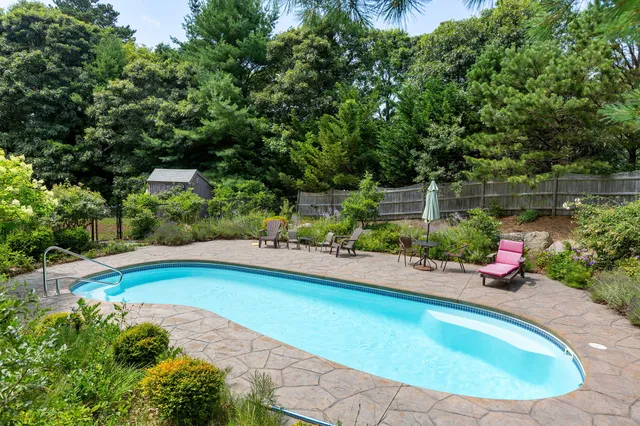 a view of pool with lawn chairs and plants