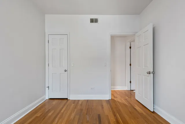 a view of an empty room with wooden floor and closet