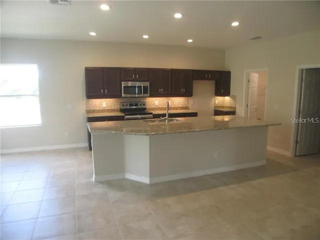 a kitchen with stainless steel appliances granite countertop a sink and a refrigerator