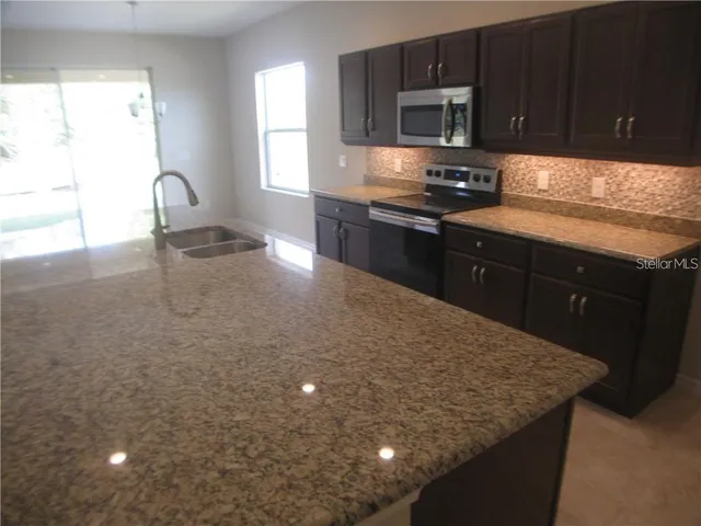 a kitchen with stainless steel appliances granite countertop a sink stove and microwave