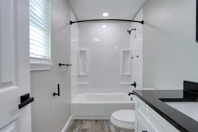 a bathroom with a granite countertop sink toilet and shower