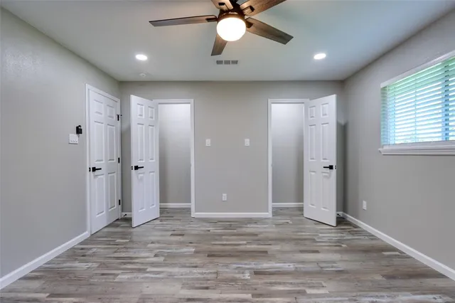 a view of an empty room with window and wooden floor