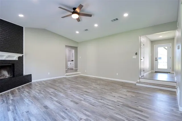 a view of empty room with wooden floor and fireplace