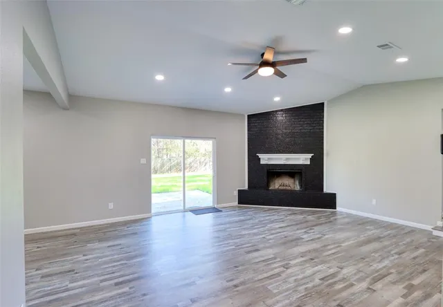 a view of an empty room with a window and fireplace