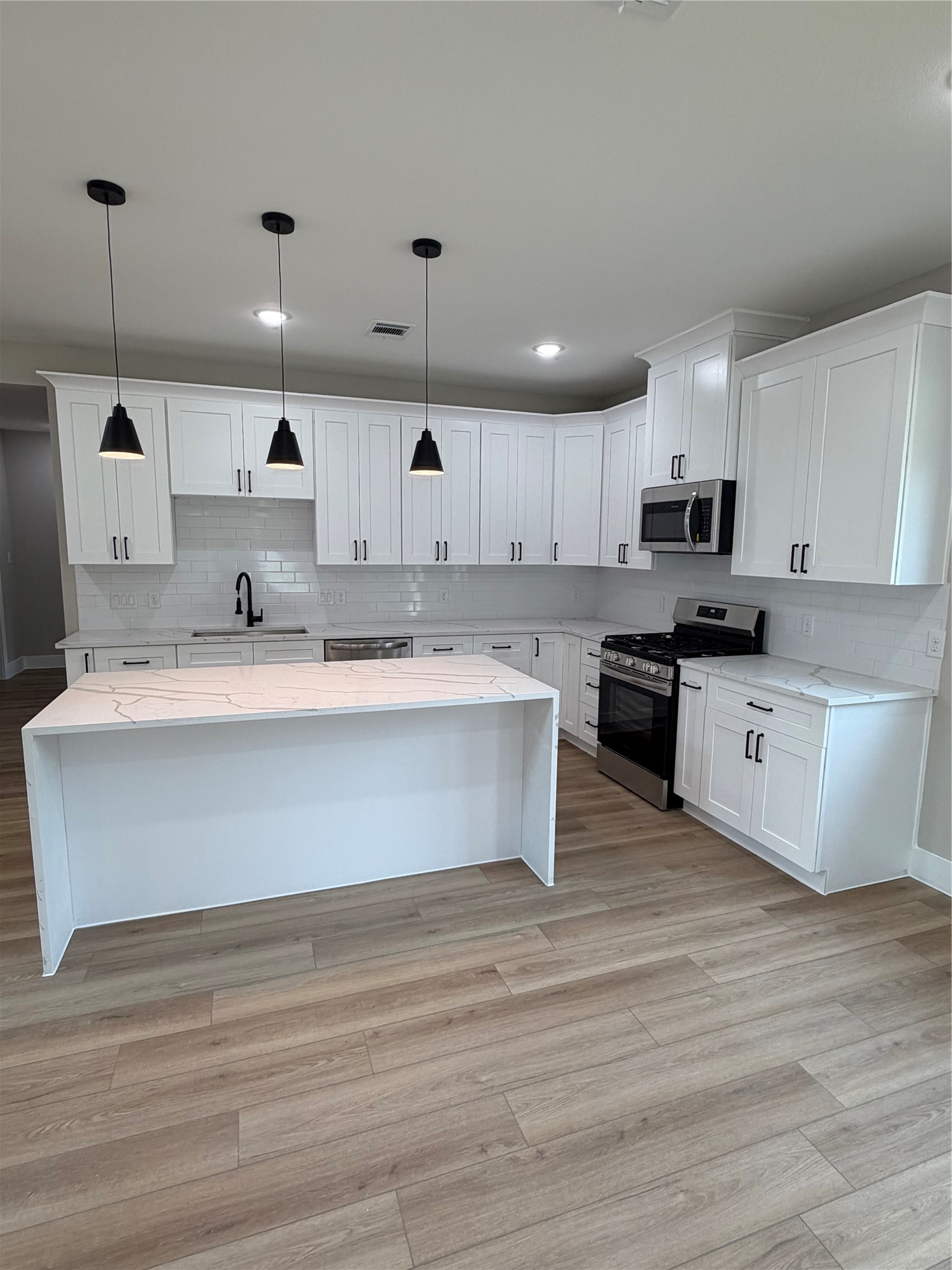 2514 Liguria Lane Spring, TX 77388 - Photo 7 of 25 a large kitchen with stainless steel appliances granite countertop a stove a sink dishwasher a microwave oven and a white countertops with wooden floor