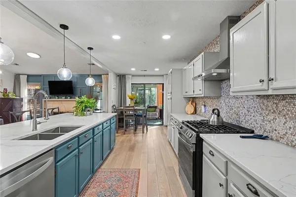 a kitchen with kitchen island granite countertop a sink a counter space appliances and cabinets