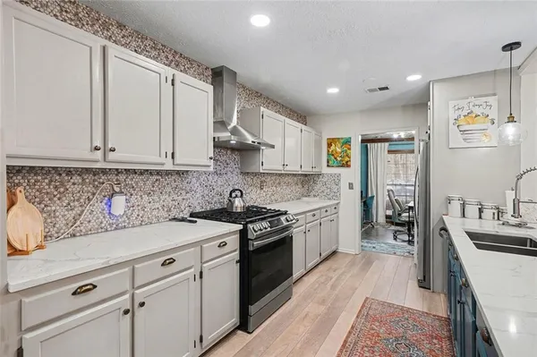 a kitchen with kitchen island granite countertop a sink cabinets and stainless steel appliances