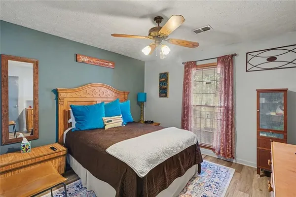a bedroom with a bed a dresser and potted plant