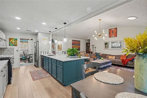 a open kitchen with stainless steel appliances kitchen island granite countertop a table and chairs in it
