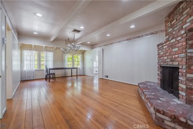 a view of an empty room with wooden floor and a fireplace