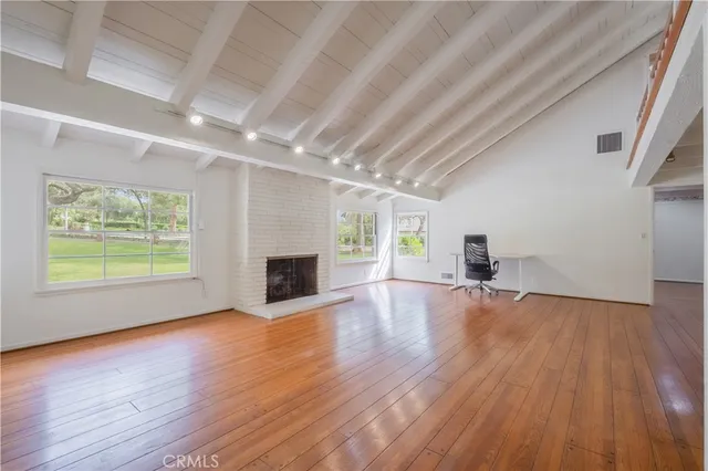 a view of empty room with wooden floor and fireplace