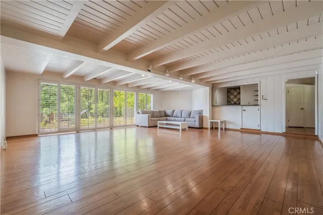 a living room with hard wood floors and a kitchen