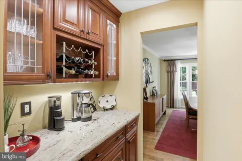 a spacious kitchen with stainless steel appliances granite countertop a refrigerator a sink dishwasher a dining table and chairs with wooden floor