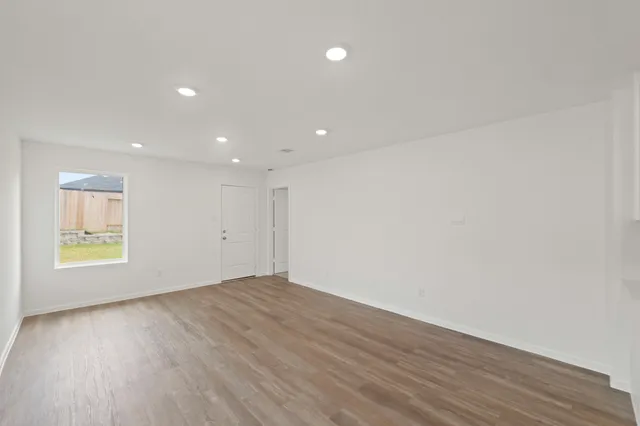 an empty room with wooden floor and window