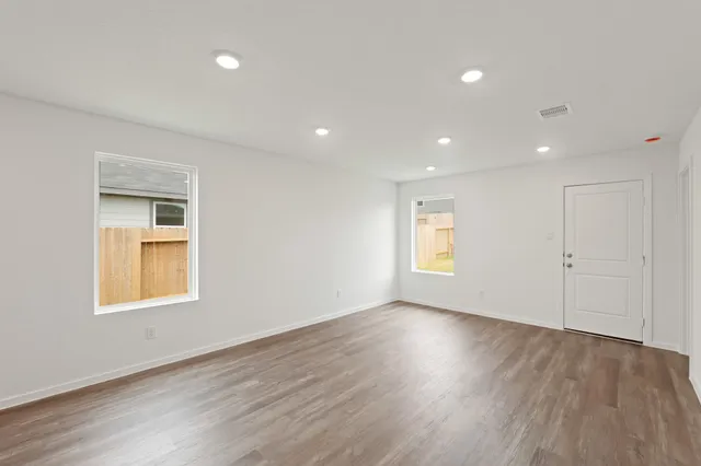 a view of an empty room with wooden floor and a window
