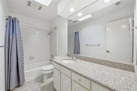 a bathroom with a granite countertop sink a toilet and shower