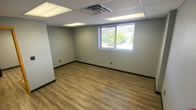 a view of an empty room with wooden floor and a window
