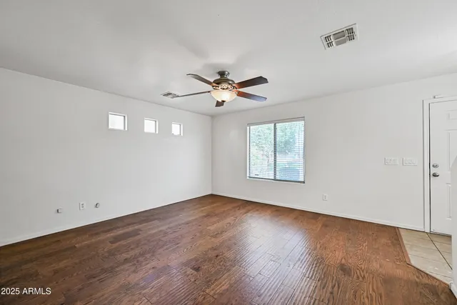 an empty room with wooden floor and ceiling fan